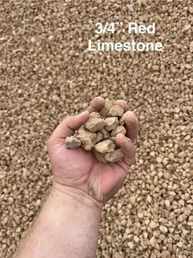 Hand holding 3/4" red limestone gravel against a textured gravel background.
