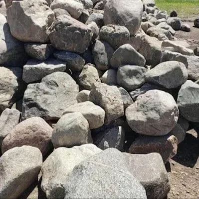 Piled natural rocks in various sizes on a construction site for landscaping and building materials.