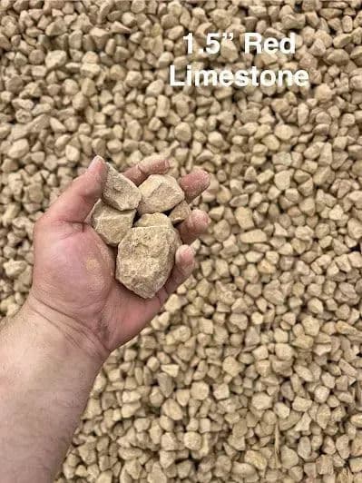 Hand holding 1.5-inch red limestone stones with a textured gravel background.