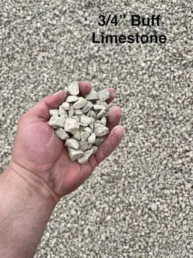 Hand holding 3/4" buff limestone against a gravel background for construction use.