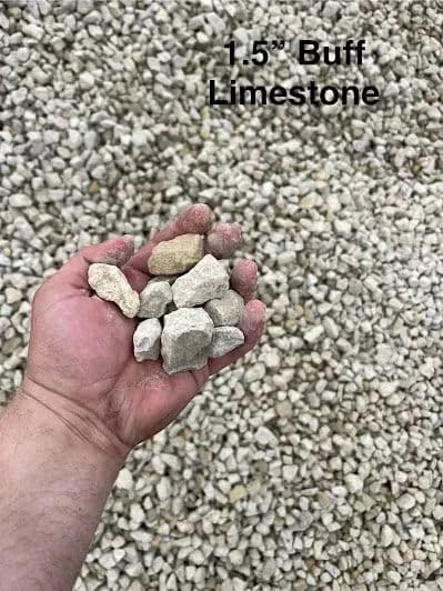 Hand holding 1.5" buff limestone stones over a pile of gravel. Ideal for landscaping projects.