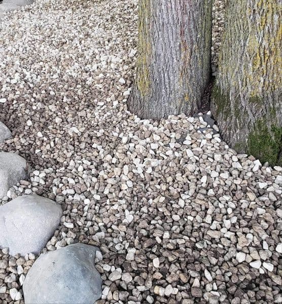 Decorative garden landscape with gravel stones and tree trunks for natural aesthetics.