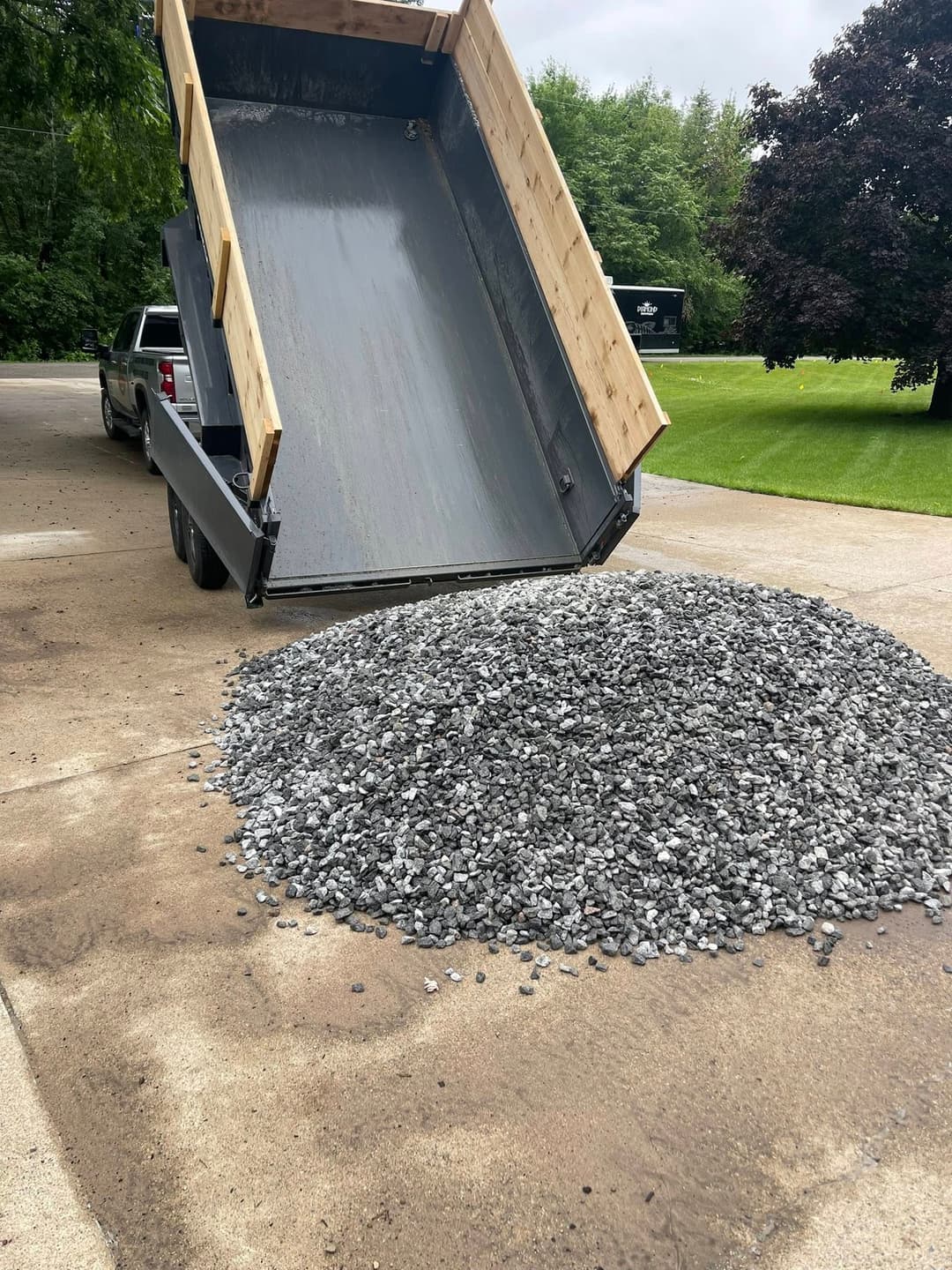 Dump truck unloading a large pile of gravel on a concrete surface.