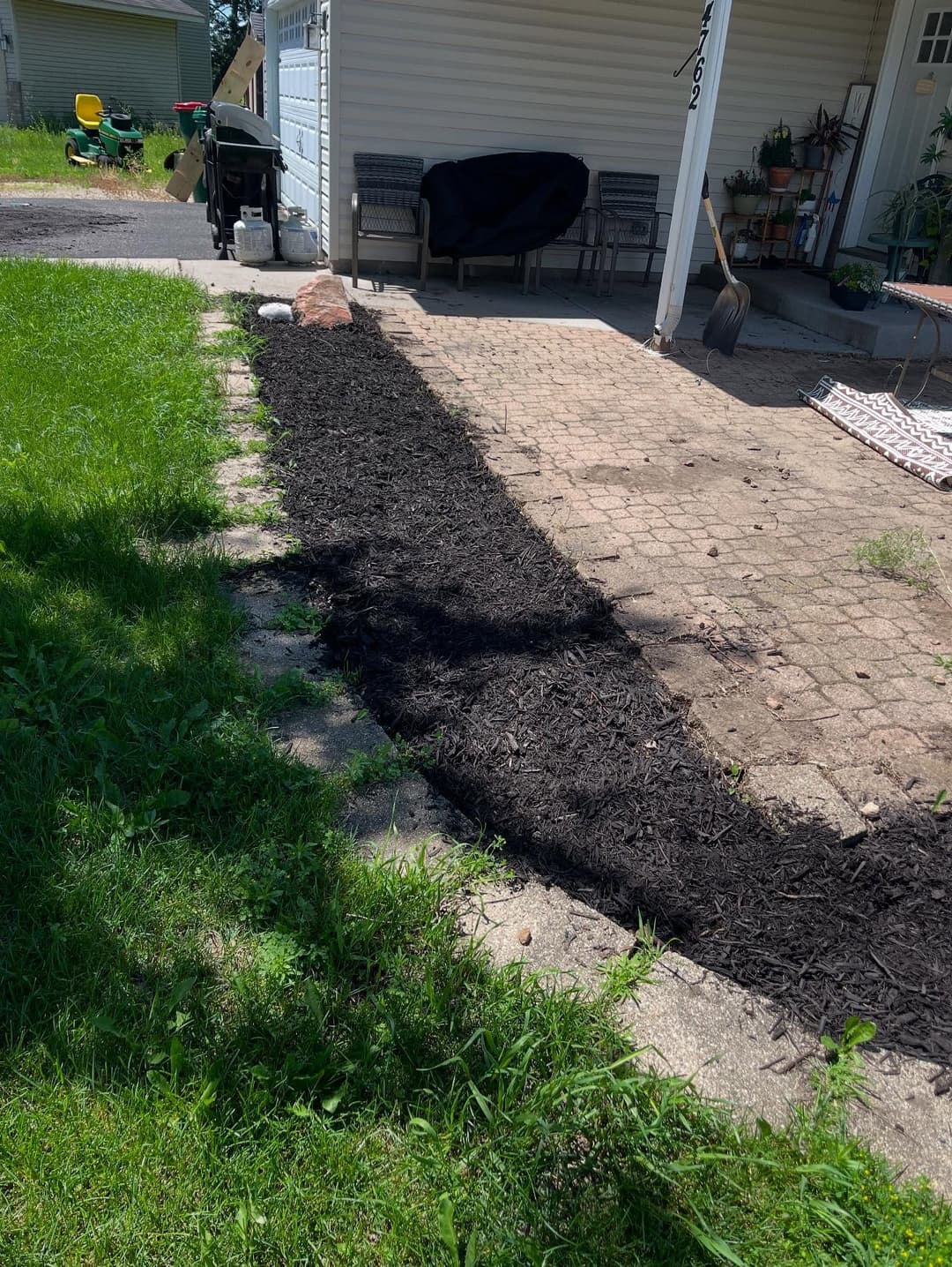 Garden landscaping with freshly spread mulch along a stone pathway and grassy area.