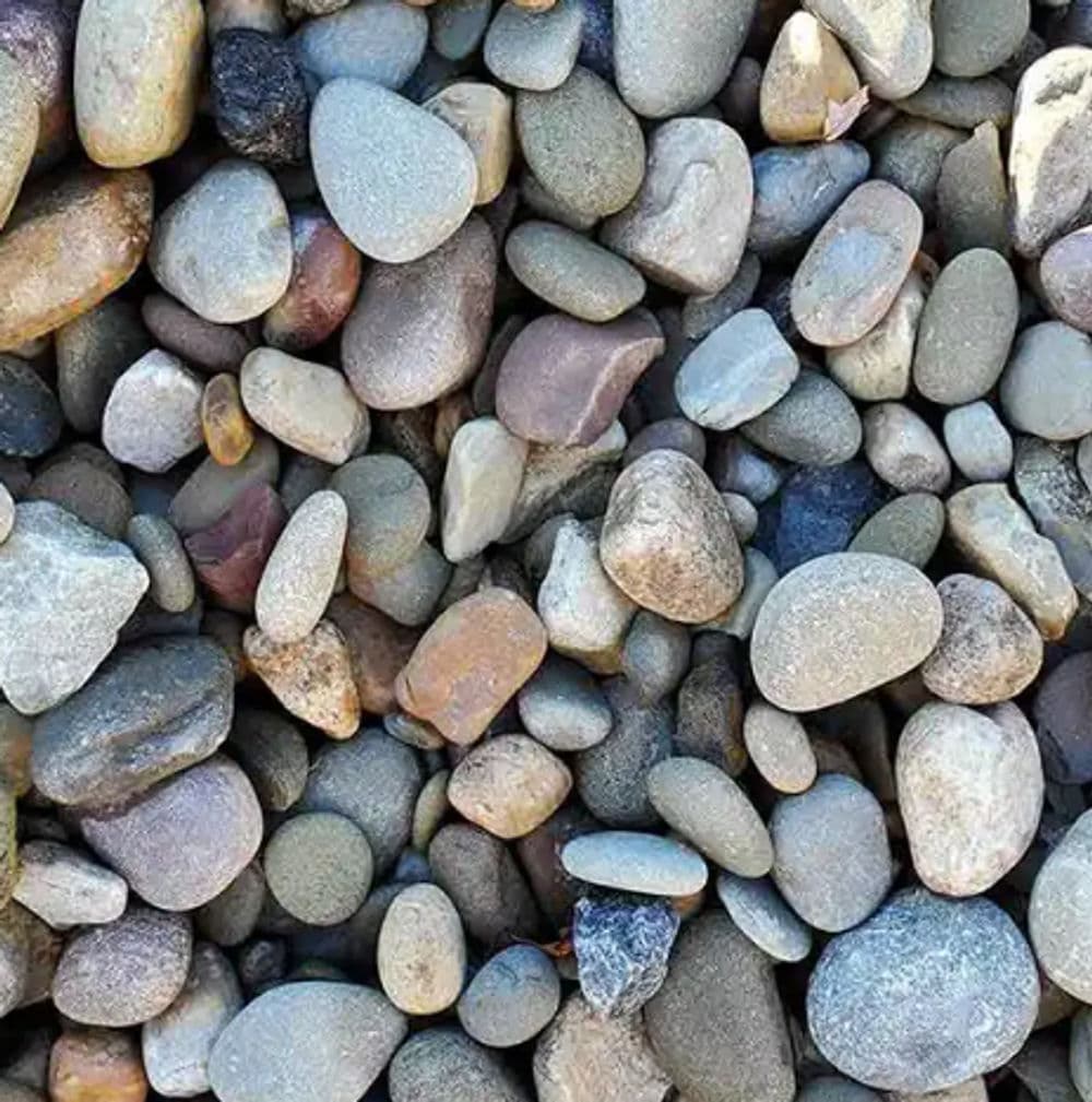 Variety of smooth river stones in various colors and sizes on a textured surface.